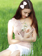 Charming teen peach with a bow in her hair undressing and showing luxurious body in a field.